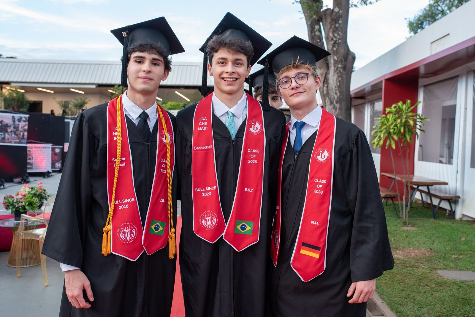 Enzo with two classmates at their IB graduation, in caps, gowns and Class of 2026 stoles